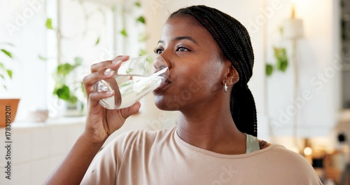 Photos Home, hydration and woman drinking water in kitchen for natural nutrients, thirsty and detox