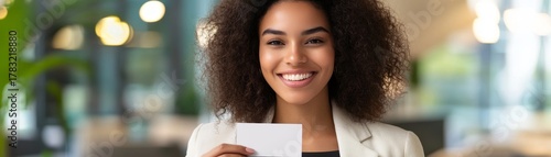 Confident woman holding a card in a modern office environment.