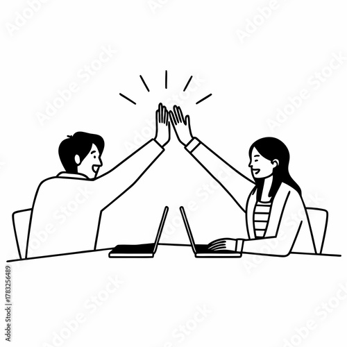 Successful business people giving each other a high five while working on laptop in coworking