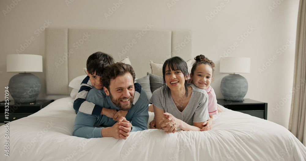 Fototapeta premium Parents, children and portrait on bed with play, smile and bonding for love with pyjamas at house. People, mom and dad with kids, happy or relax in morning, care and laugh at family home in Spain