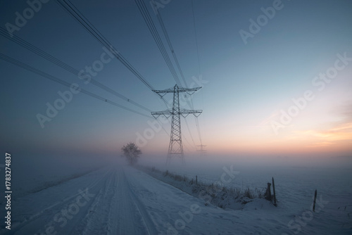 Canvastavla Snow-covered rural road with power lines disappearing into fog at dawn