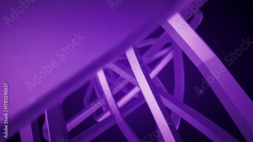 A close-up shot of intersecting, solid purple bars and curved shapes against a dark background, creating an abstract, 3D structure