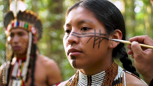 young indigenous woman with traditional facial markings, beaded necklaces, serene. hand draws lines on cheek in sun-dappled ancient forest. concept of cultural ritual and natural beauty
