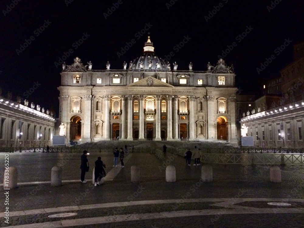 Fototapeta premium Illuminated St. Peter’s Basilica at Night in Vatican City with Tourists