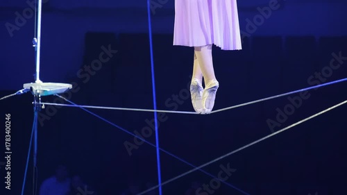 Close-up of an aerial acrobat walking on a tightrope on tiptoes. The image captures the performer balance and elegance, showcasing the precision and grace needed for this high-flying act