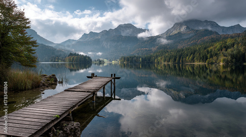Fototapeta Naklejka Na Ścianę i Meble -  Wooden dock extending into a calm lake surrounded by mountains and trees