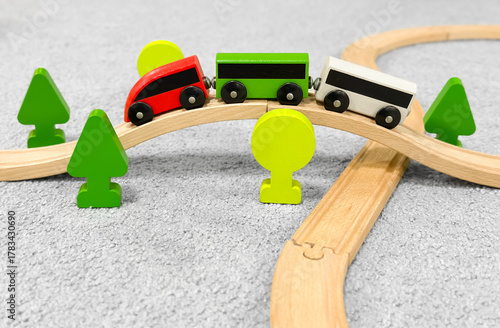 Children's wooden railway with bright carriages, a wooden figurine of a man, wooden toy trees. eco-friendly wooden toys