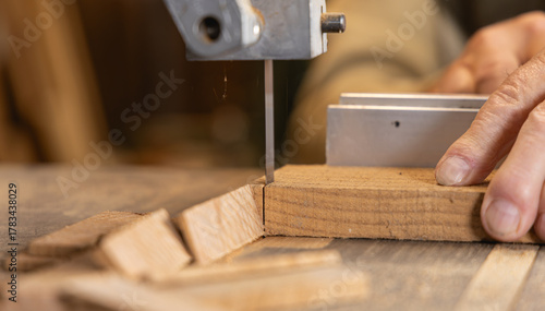Fotografie Gros plan sur un menuisier découpant une planche de bois à la scie à ruban