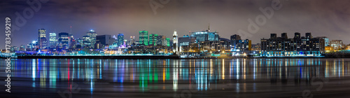Wide panorama of downtown Montreal in winter. Long exposure night shot with the city lights reflected in the St Lawrence river.