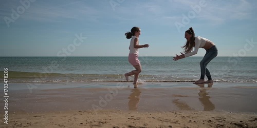 A mother and her daughter are running and enjoying on the beach