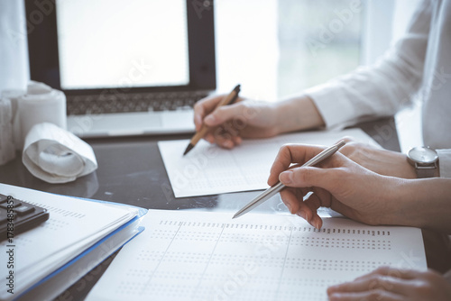 Two accountants use a laptop computer for counting taxes or revenue balance. Business, audit, and taxes concepts