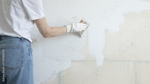 Billede på lærred Unknown female construction worker applying plaster with putty knife, smoothing