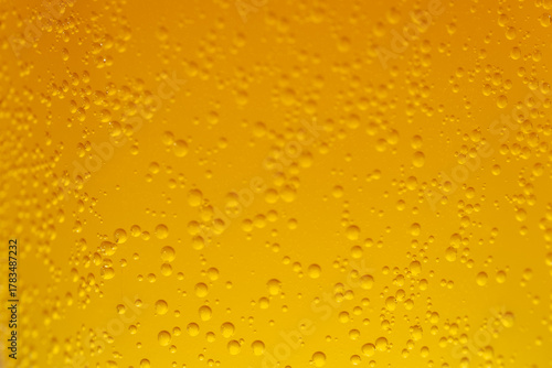 Fotomural Extreme close-up of a yellow-orange carbonated liquid with rising bubbles creating a textured and bright background