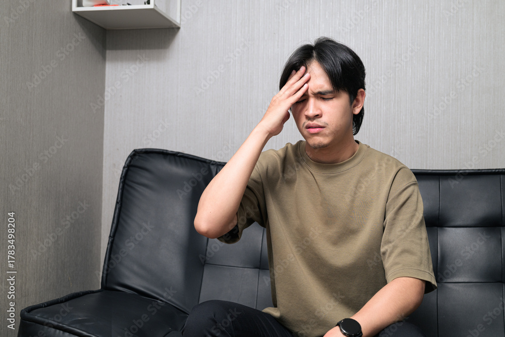 Fototapeta premium Portrait of handsome Young Asian Thai man looking television while sitting on sofa