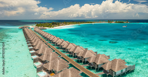 Fototapeta Naklejka Na Ścianę i Meble -  Panoramic view luxury resort overwater bungalows. Fantastic pristine sand beach turquoise ocean water sunny blue sky. Maldives islands villas travel destination aerial backdrop summer vacation tourism