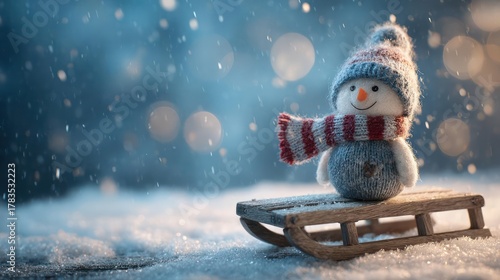 Charming knitted snowman wearing a striped hat and scarf sits on a wooden sled during a gentle snowfall