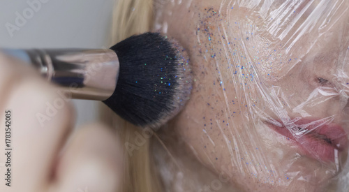 Microplastics in cosmetics. A woman applied a care cream to her skin, now it is covered with plastic particles and microbeads. Cosmetics toxicity concept
