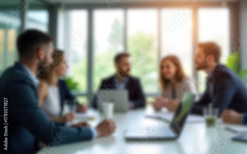 Out of focus office background with business people in a meeting. Modern workplace interior with natural light from large windows. High quality