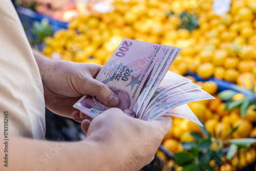Turkish lira banknotes in hand against the background of vegetables at the farmer's market. The concept of consumer economy and inflation of the national currency of Turkey.