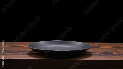 Black ceramic plate on wooden table with dark background, simple and elegant design for modern dining setting