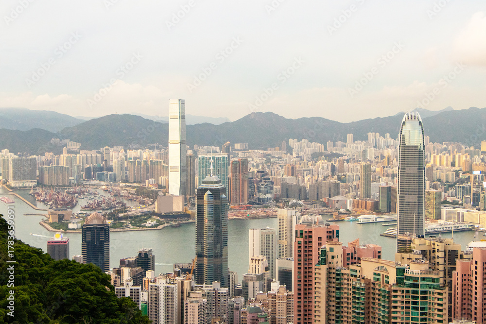 Naklejka premium Skyscraper scenery aerial view on top of buildings at evening in town Hong Kong. City with soft orange sunlight in evening beautiful with hotels and office tower large river flows through center.