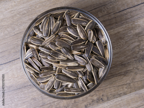 Striped sunflower seeds in a glass bowl on a wooden table.