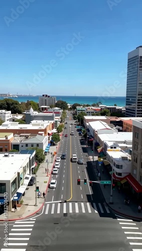 Vertical aerial view of a downtown city street leading to the ocean.