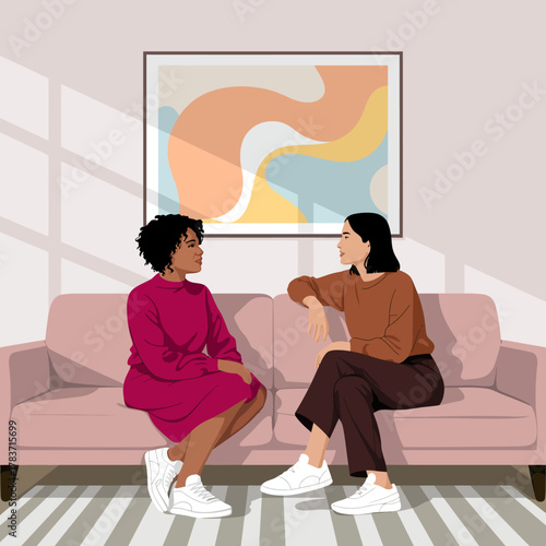 An intimate scene shows two women sitting on a stylish couch, engaged in a heartfelt conversation, showcasing connection and human emotions in a domestic setting.
