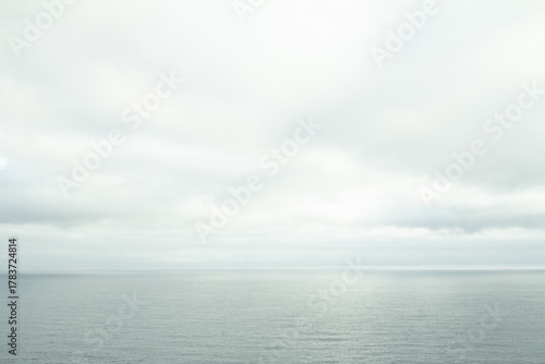 Fototapeta Naklejka Na Ścianę i Meble -  Calm blue sea meeting a tender sky with soft clouds — peaceful coastal scenery from the Faroe Islands, ideal for travel and nature lovers.