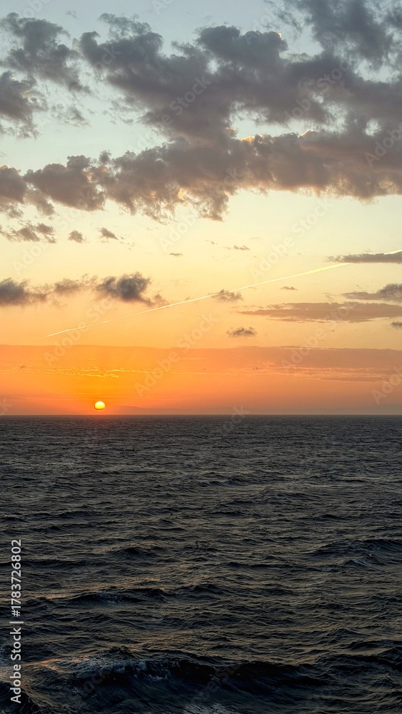 Obraz premium Stunning natural seascape showing warm colors of sunset above the horizon and calm waves of the sea.
