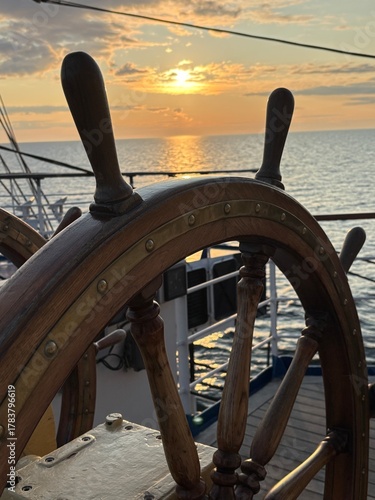 an antique ship's wheel at sunset at sea