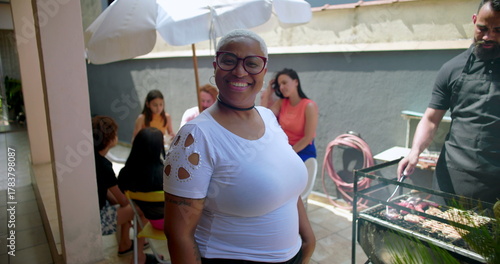One hispanic black latina Woman smiling confidently at a backyard barbecue gathering, highlighting joy, inclusivity, and connection in a casual social setting with family and friends