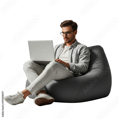 Full body young smiling happy man sitting in bag chair, holding and using on laptop isolated on white background