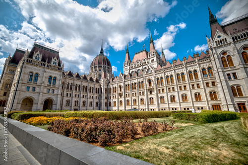 Budapest, Hungary - July 27, 2025: Exterior view of the Hungarian Parliament Building showcasing Neo-Gothic architecture and intricate stonework under a dramatic sky
