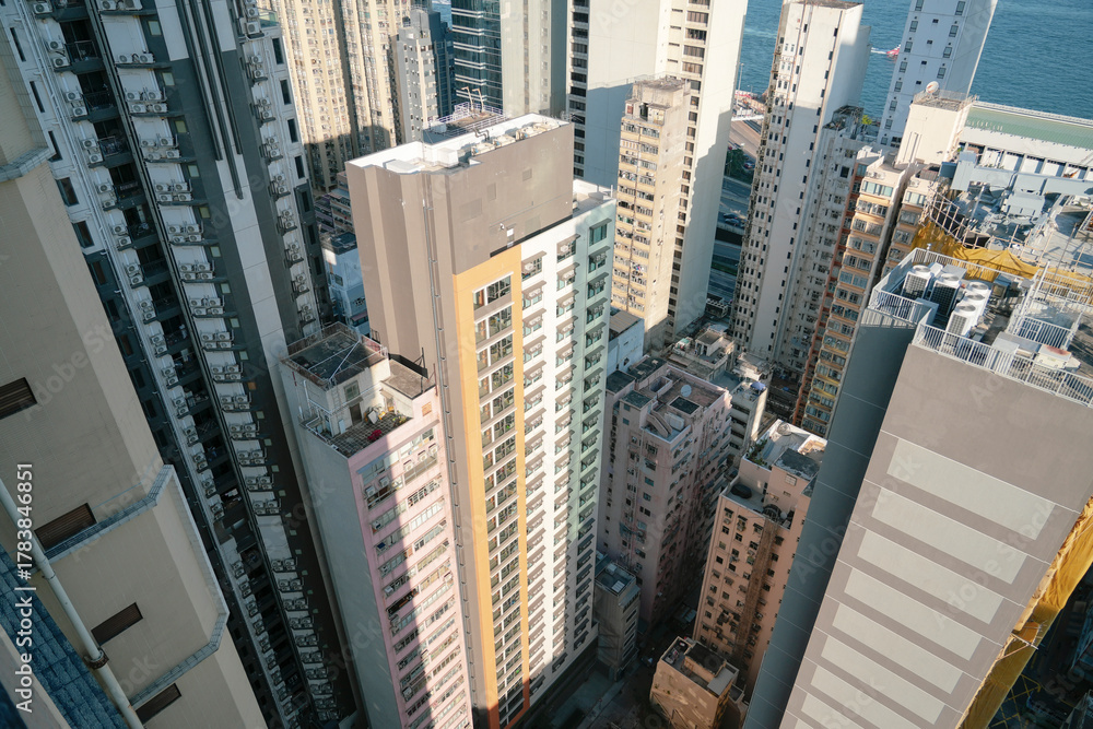 Fototapeta premium Tall buildings in a crowded city are visible, showing various architectural styles and colors. This view captures the bustling atmosphere of the urban landscape by the water