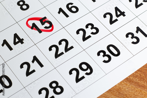 Number 15 marked in the calendar with red color circle to point important date on the wooden table