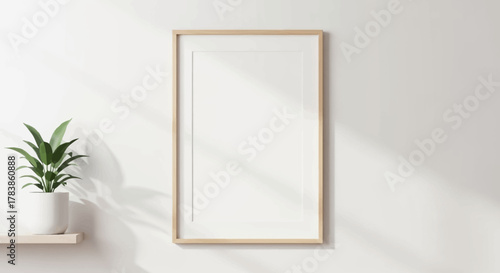 Blank wooden frame on a white wall with plant, natural light shadows, creating a minimalist room decor aesthetic