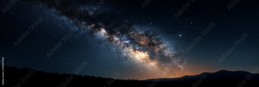 Fototapeta premium A breathtaking panorama of the Milky Way illuminates the night sky, casting a magical glow over a serene mountainous landscape, inspiring awe in nature's majesty.