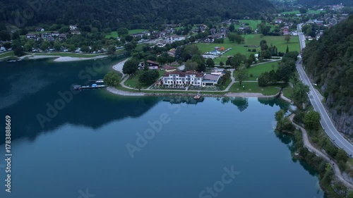 Aerial view of Pieve di Ledro village with lakeside shoreline and surrounding green hills
