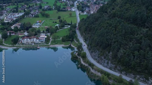 Aerial drone view of Pieve di Ledro with village, lakeside shoreline and forested hills
