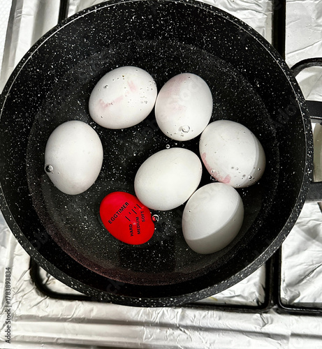 Boiling eggs in a pot with a doneness indicator. Kitchen cooking process, top view.