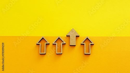 Wooden arrows pointing up on yellow background - business growth, leadership and competitive advantage concept