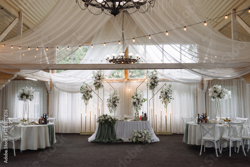 Wallpaper Mural Beautiful wedding reception setup with white flowers, green accents, round tables, and soft lighting in a wooden hall with draped fabric ceiling. Concept: celebration, romance, event design, luxury. Torontodigital.ca