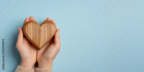 Charity volunteer donation concept banner with copy space. Help to needy people. Hand holding wooden heart on blue background.