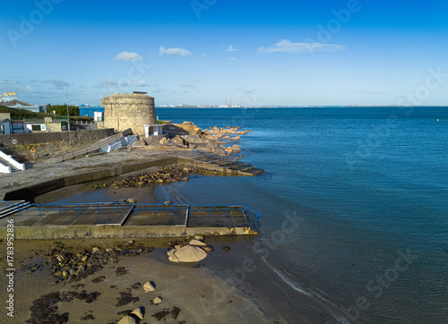 Fotografie A beach with a dock and Martello Tower Number 14, Seapoint, Blackrock, Dublin