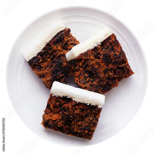 Christmas fruit cake slices with marzipan. Top down view plate isolated on a white background.