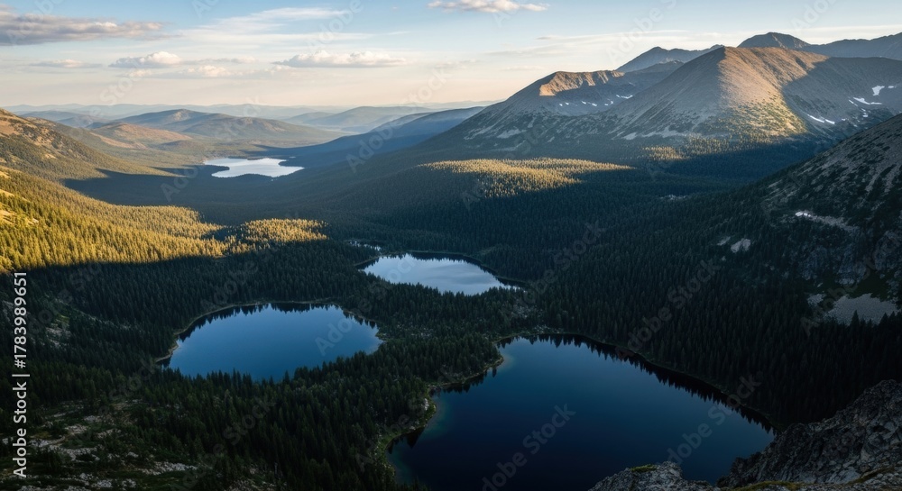 Obraz premium Scenic mountain range with pristine alpine lakes. Aerial perspective of a vast wilderness valley. Outdoor adventure and eco tourism destination. Golden hour light on a forest landscape