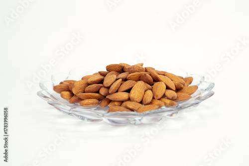 Pile of Raw Almonds in a Decorative Glass Dish on a White Background