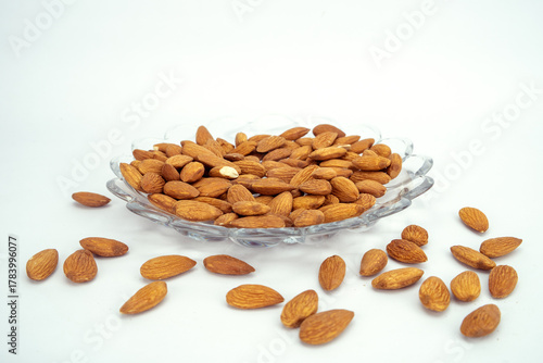 Raw Almonds Spilling Out of a Glass Serving Dish on White Background