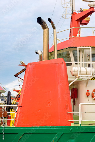 orange chimney with two exhaust pipes on the deck of a boat